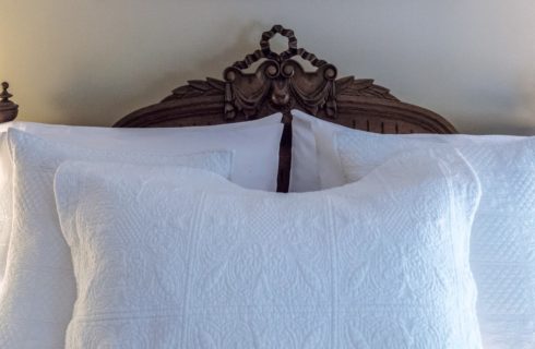 Dark wooden ornate Victorian bed with white bedding