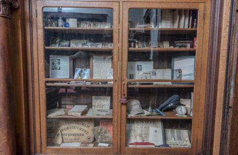 Ornate built-in wooden cabinet with glass doors filled with antique trinkets