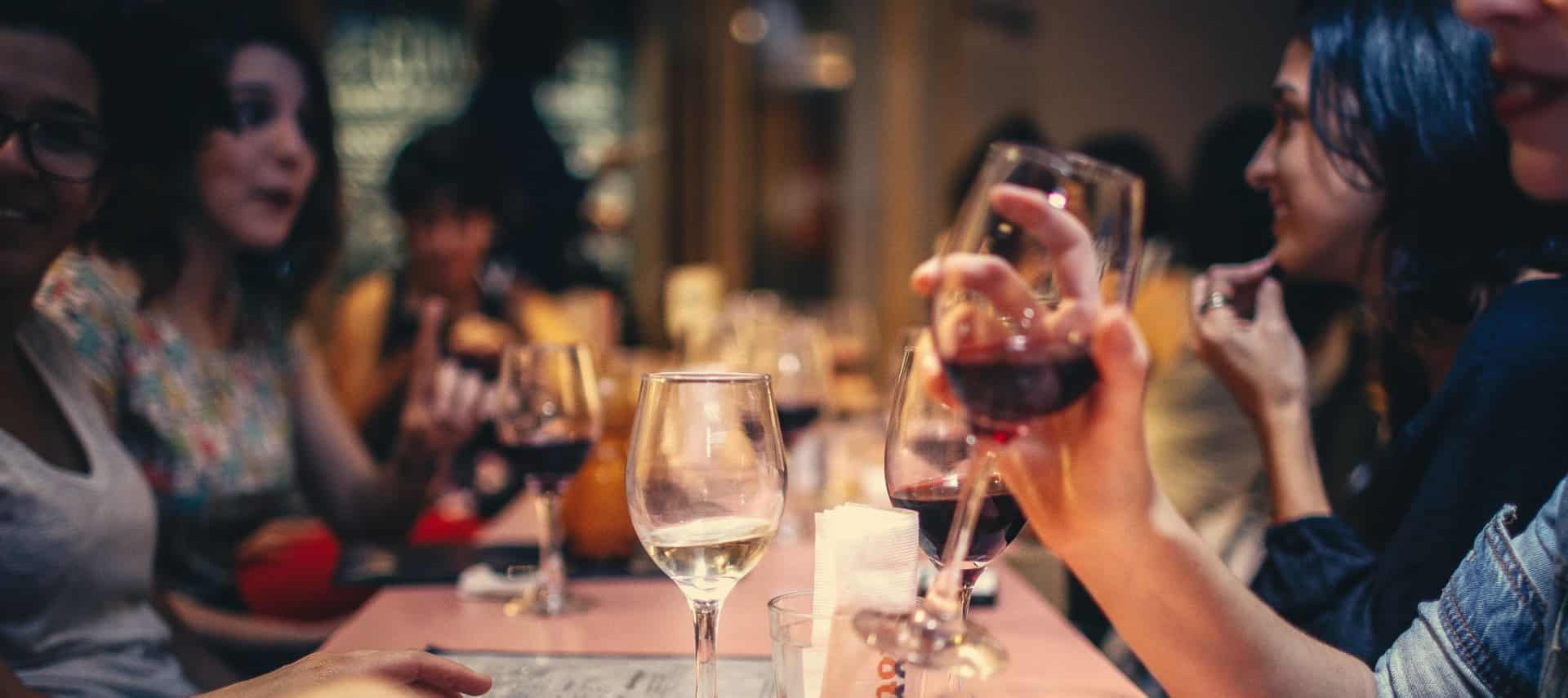 People at a restaurant sitting at a table talking, laughing, and drinking wine